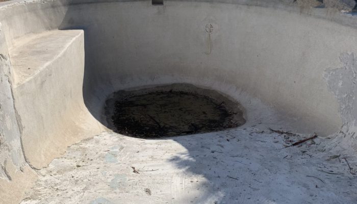 Concrete pool with pebble interior and structual cracks.
