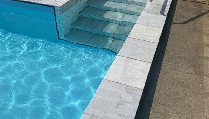 Block pool with Aqualux Light Blue with Parisan Blue Lime Stone coping and grey mosiac tiles.